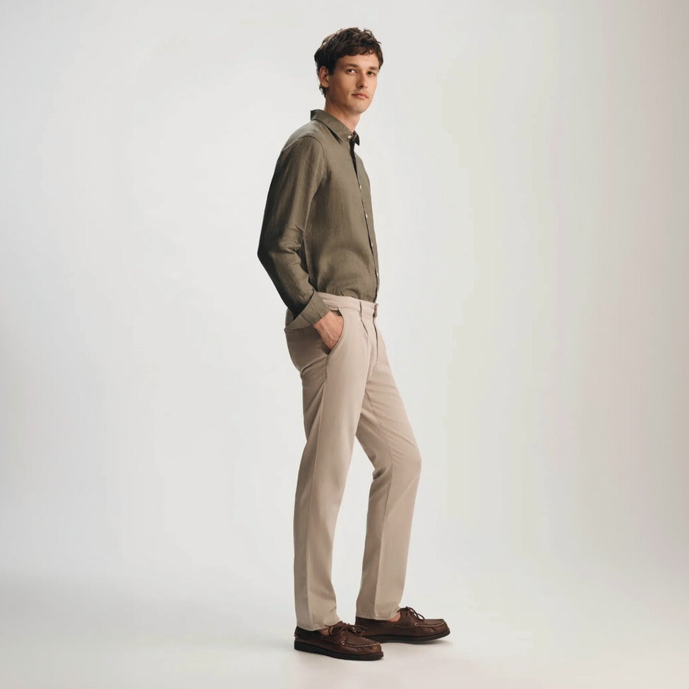 Man wearing a green shirt and beige pants on a white background