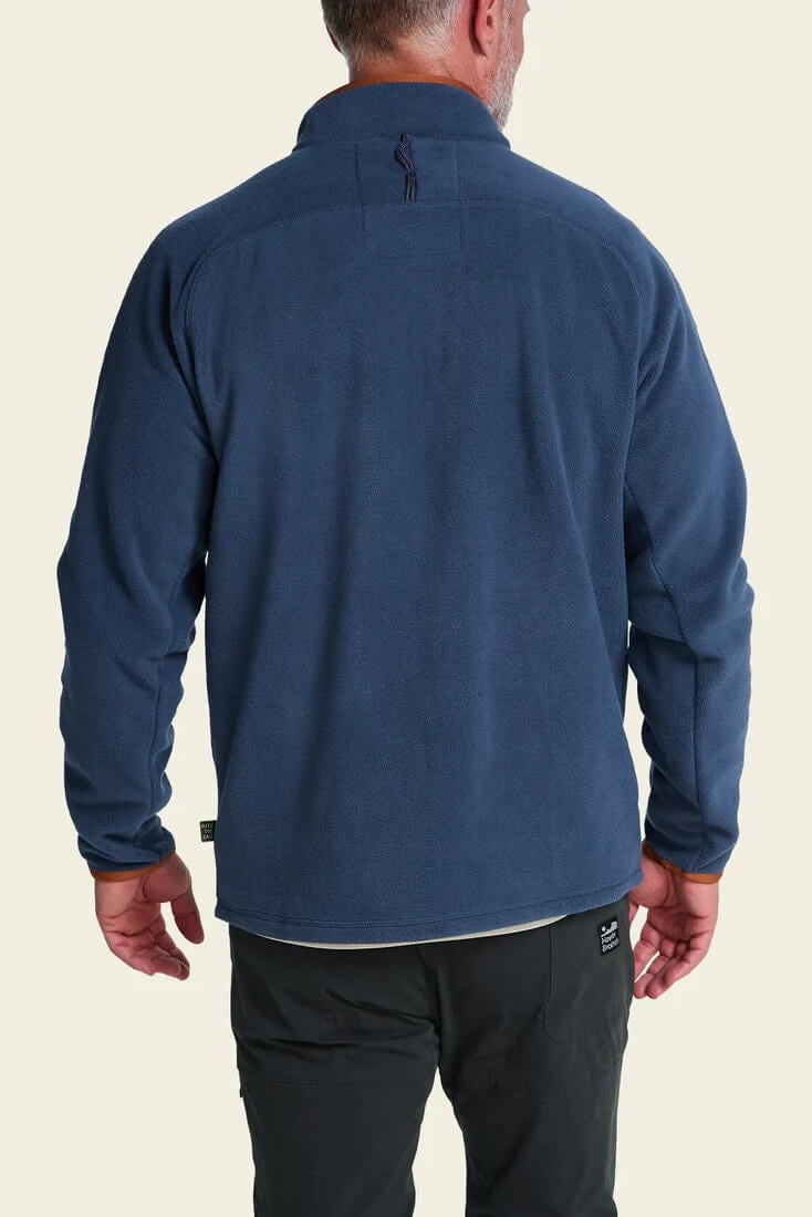 A man viewed from the back wearing Howler Bros Free Range Fleece Pullover in Nightfall, set against a solid light beige background.