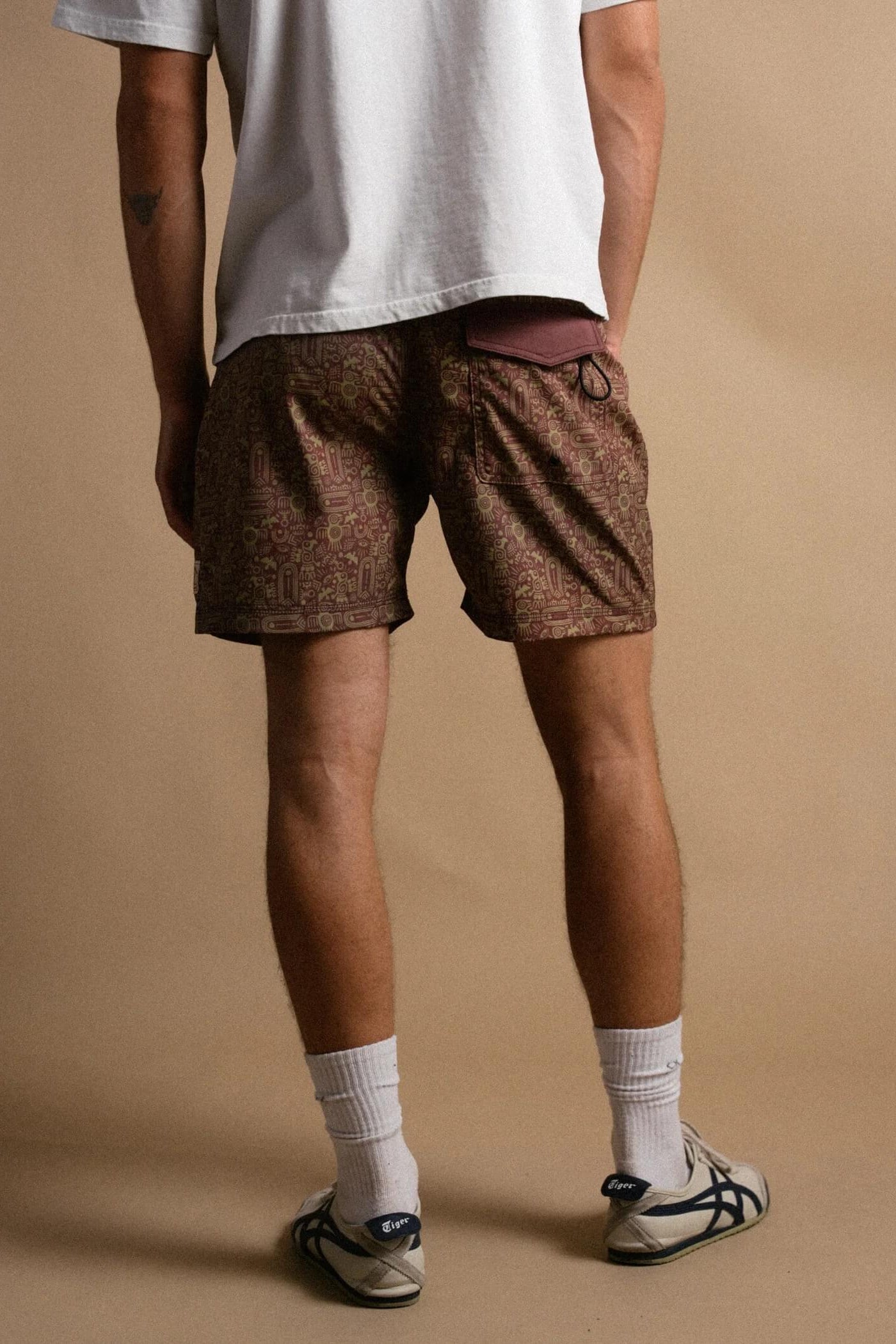 Person wearing patterned shorts and white socks on a beige background
