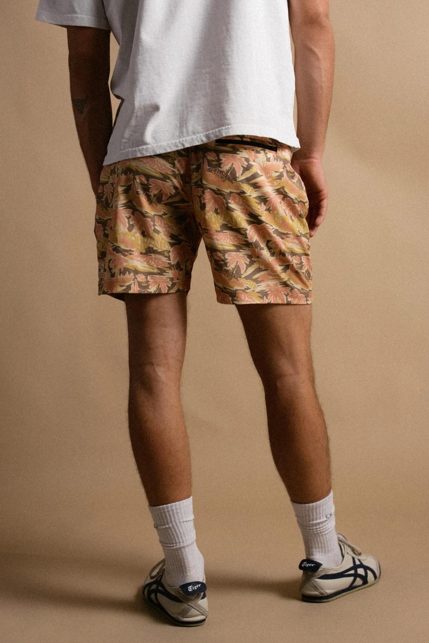 Person wearing camouflage shorts on a beige background