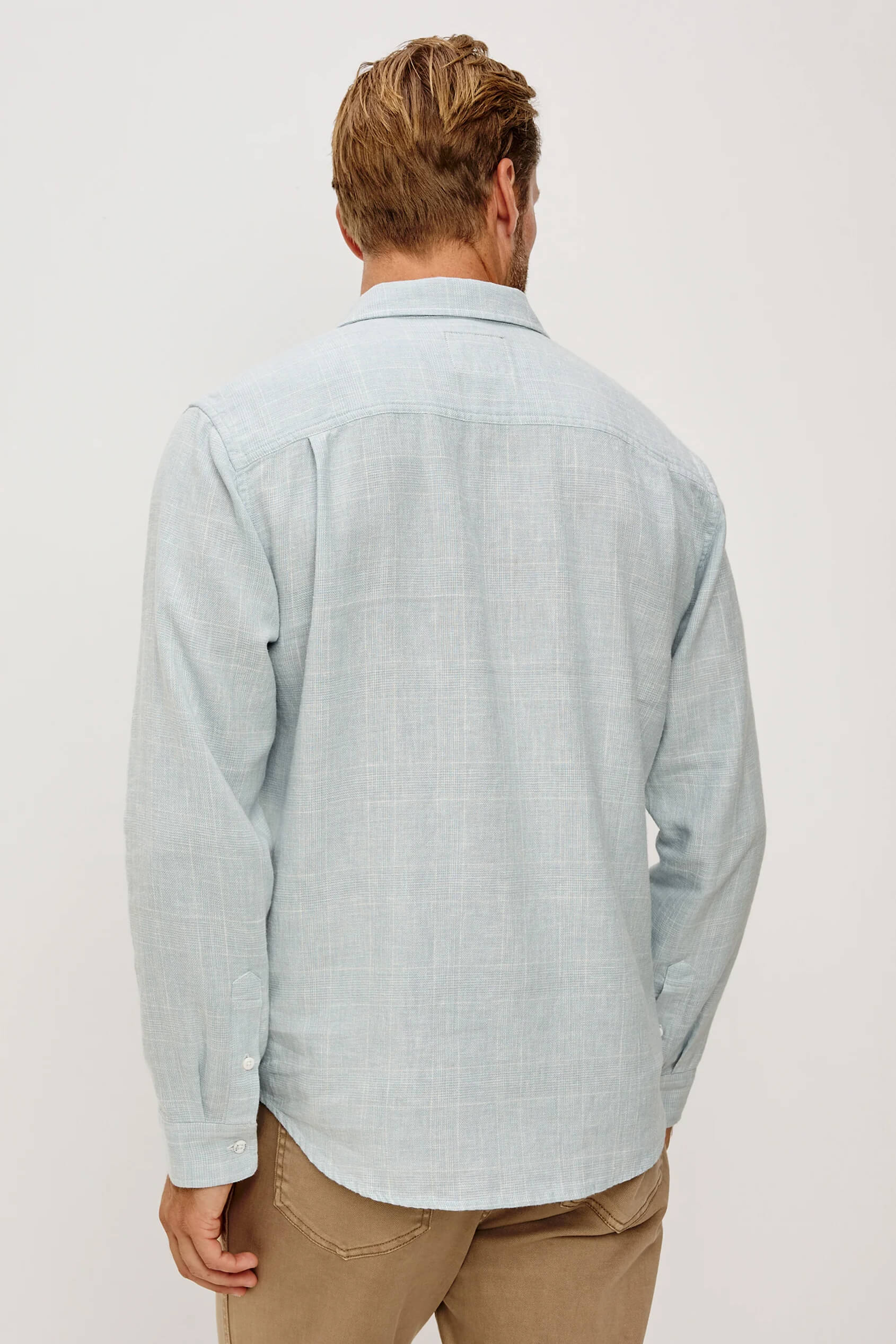 Man wearing a light blue checkered shirt against a white background
