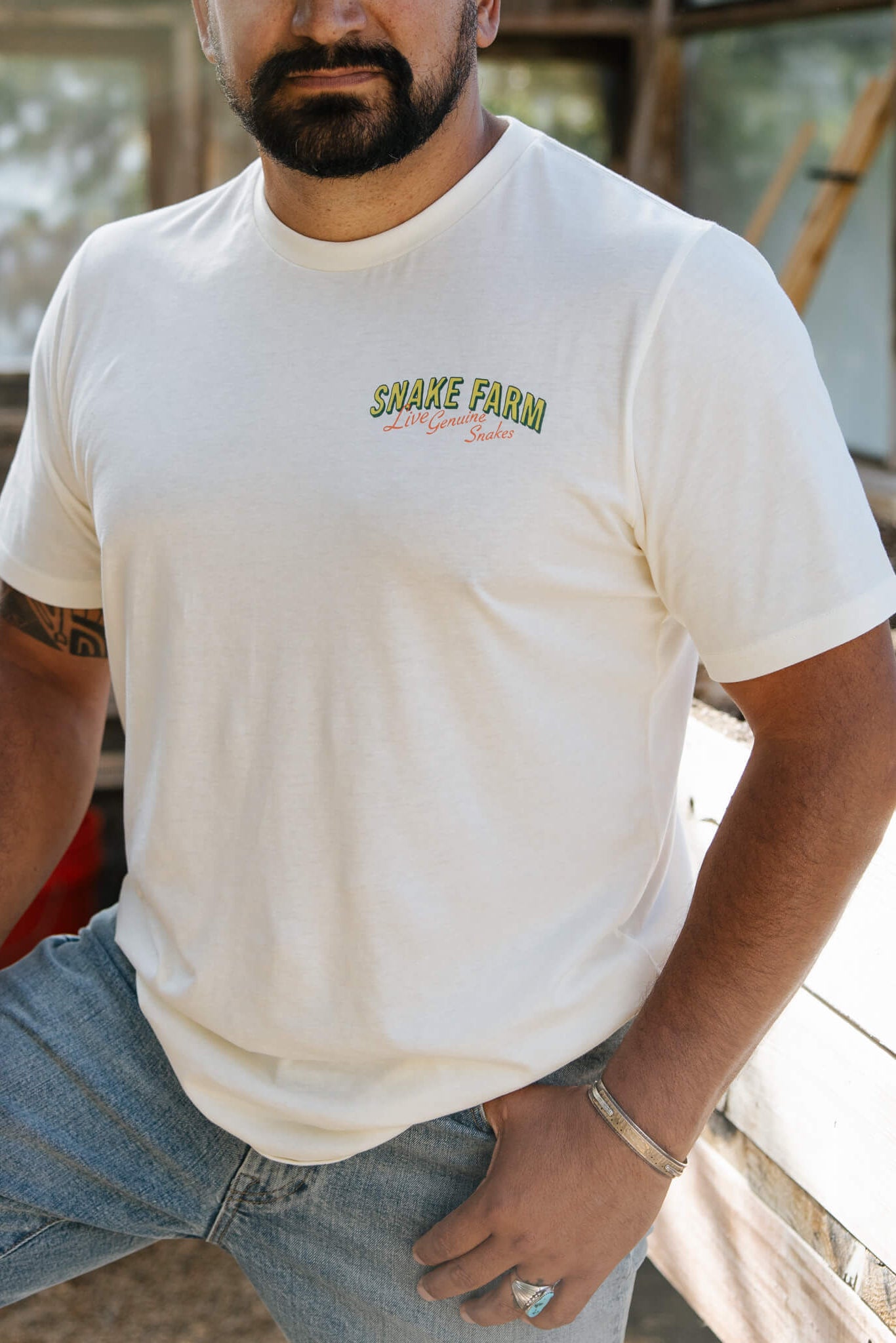 Man wearing a white t-shirt with 'Snake Farm' logo outdoors