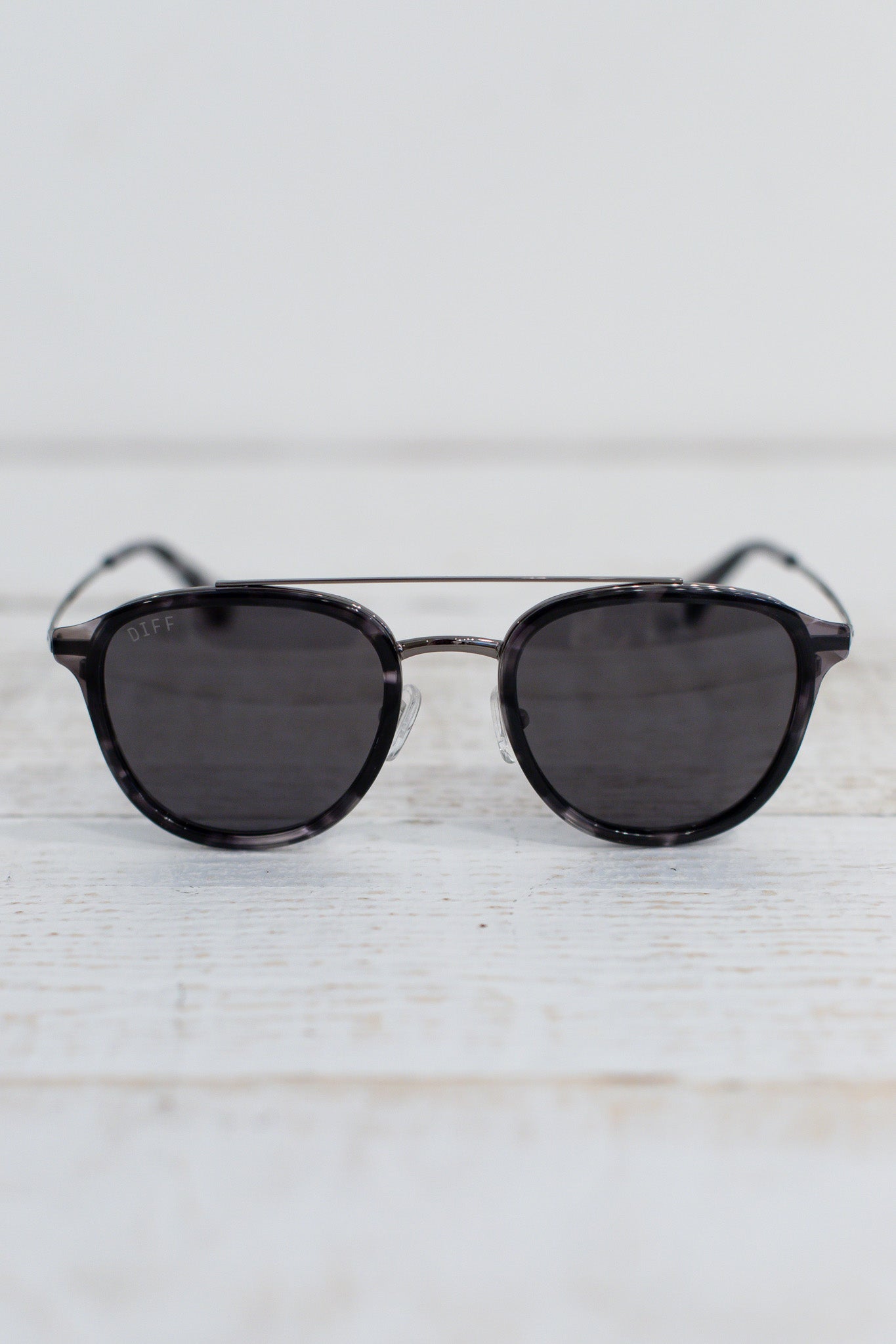 Sunglasses with dark lenses and thin frame on a light wooden surface